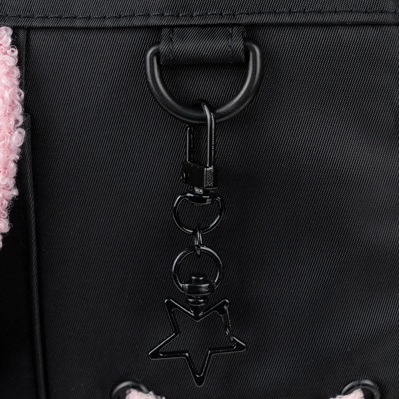 Zbliżenie na dekoracyjny element w kształcie gwiazdki, umieszczony na frontowym panelu czarnego plecaka Aggretsuko.