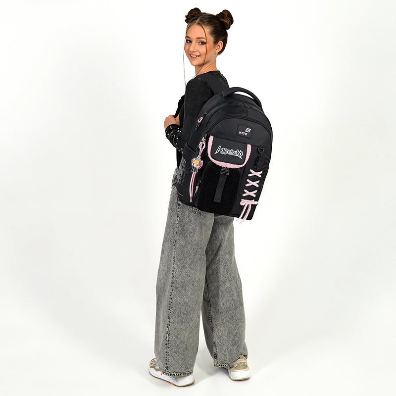 Nastolatka trzymająca stylowy czarny plecak na jednym ramieniu.