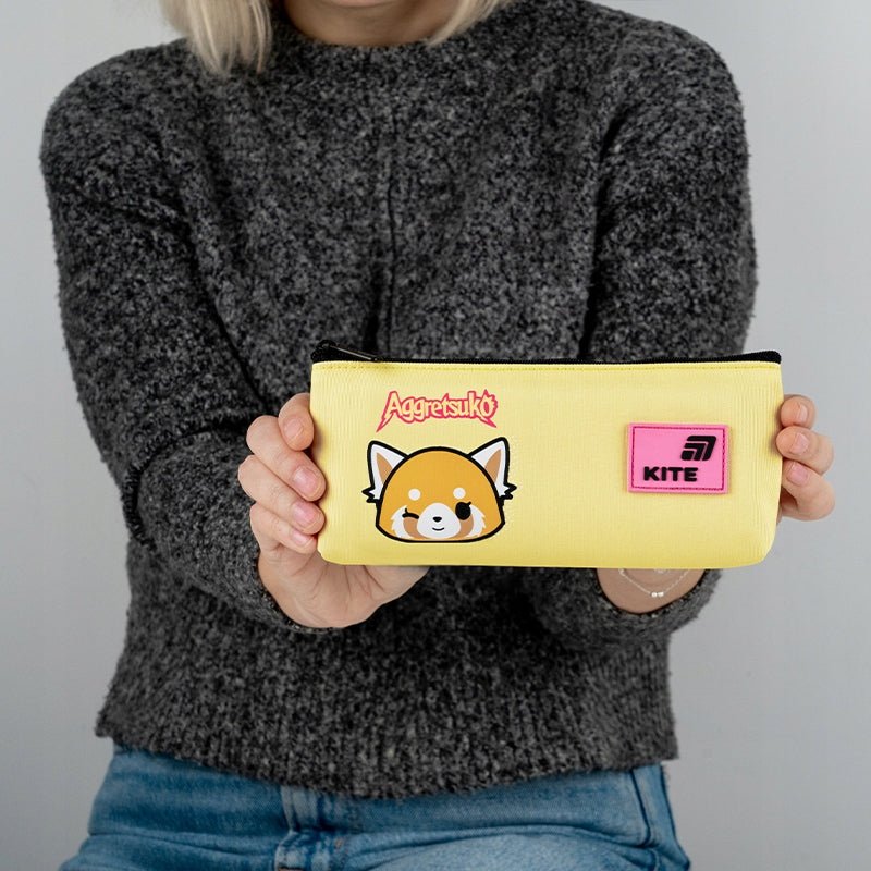 Dziewczynka trzymająca żółty piórnik dla dziewczynki z licencją Aggretsuko.