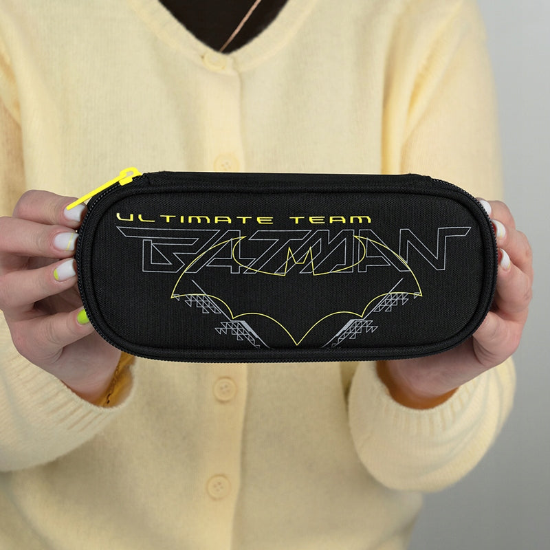 Zamknięty piórnik z logo Batmana trzymany przez ucznia.