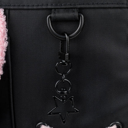 Zbliżenie na dekoracyjny element w kształcie gwiazdki, umieszczony na frontowym panelu czarnego plecaka Aggretsuko.