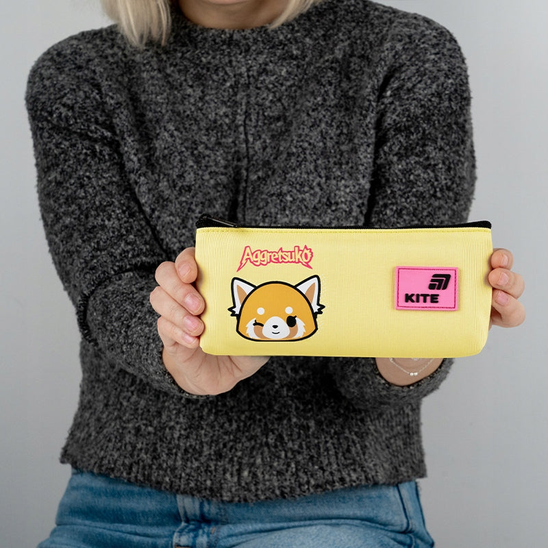 Dziewczynka trzymająca żółty piórnik dla dziewczynki z licencją Aggretsuko.