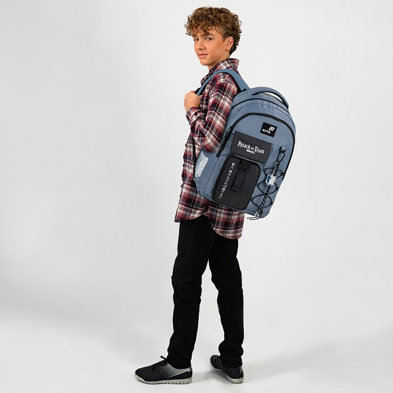 Nastolatek trzymający stylowy niebieski plecak na jednym ramieniu.