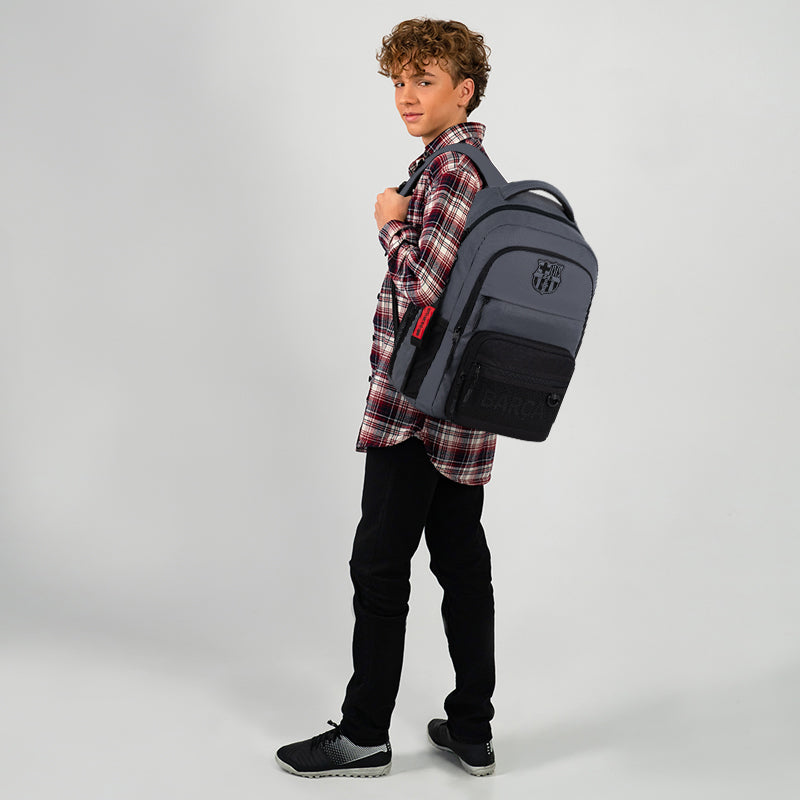 Widok nastolatka trzymającego szary plecak na jednym ramieniu.