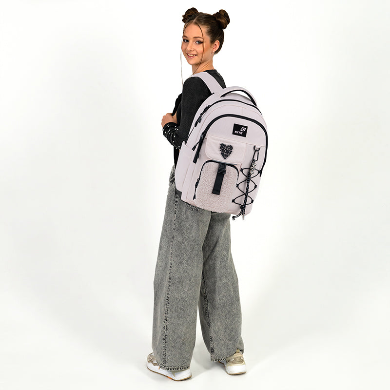 Modelka trzymająca jasnoróżowy plecak Kite na jednym ramieniu, prezentująca jego lekkość i swobodny styl.