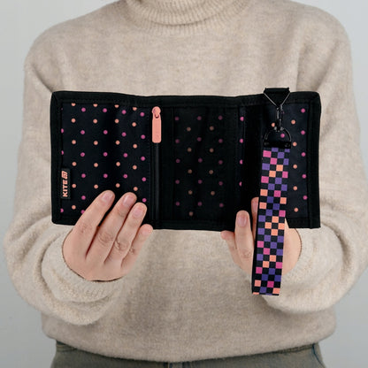 Portfel Kite w kropki wygodnie trzymany w rękach dziecka.