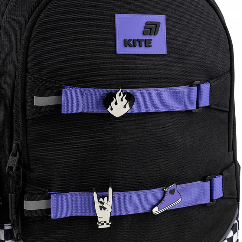 Detal trzech metalowych znaczków oraz miękkiego breloka wykonanego z materiałów mieszanych.