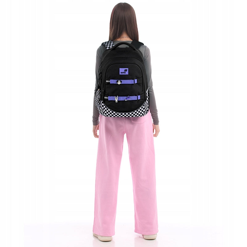 Widok plecaka na plecach nastolatki z poprawnie zapiętym pasem piersiowym, stabilizującym konstrukcję podczas chodzenia.