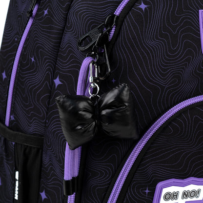 Detal ozdobnej zawieszki z materiałów mieszanych przypiętej do suwaka plecaka.